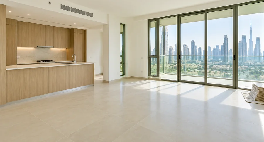 Modern Dubai apartment interior with a spacious tiled floor, fitted kitchen, floor-to-ceiling windows, and city skyline view for post-construction apartment cleaning.